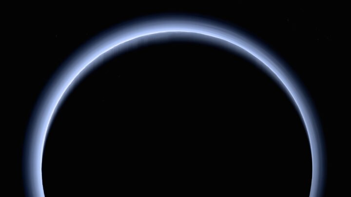 Pluto's night side ringed by a glowing blue band of atmospheric haze, photographed by NASA's New Horizons spacecraft as it flew past